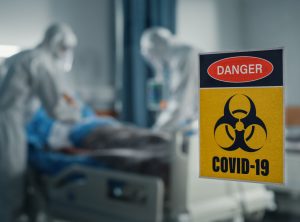 Hospital Coronavirus Emergency Department Ward: Doctors wearing Coveralls, Face Masks Treat, Cure and Save Lives of Patients. Focus on Biohazard Sign on Door, Background Blurred Out of Focus