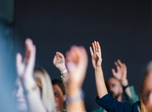A group of engaged individuals raising their hands during a business event, indicating participation and interaction in a professional setting.