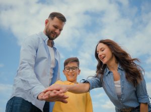 Low angle happy friendly Caucasian family parents mother father little boy son kid child hands stack team celebrate teamwork gesture enjoying together outside nature friendship unity childcare support. High quality 4k footage